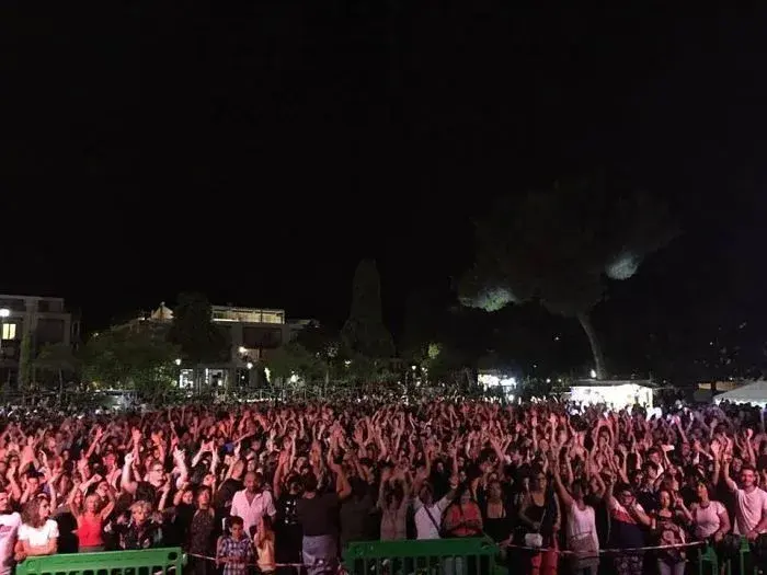 Il pubblico di un concerto serale all’aperto, tra i pini