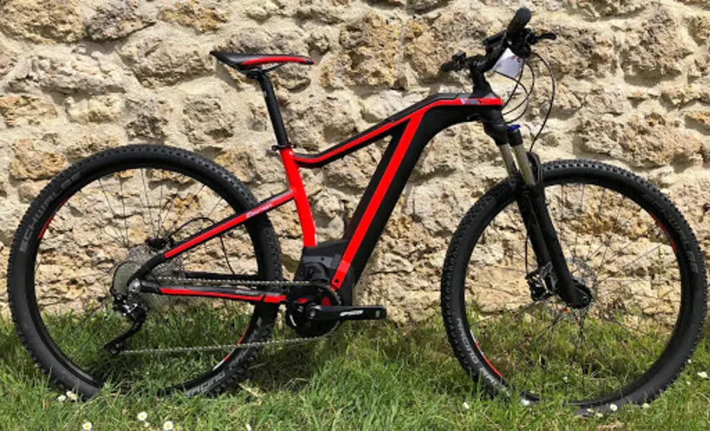 Una e-bike rossa e nera appoggiata a un muro di pietra