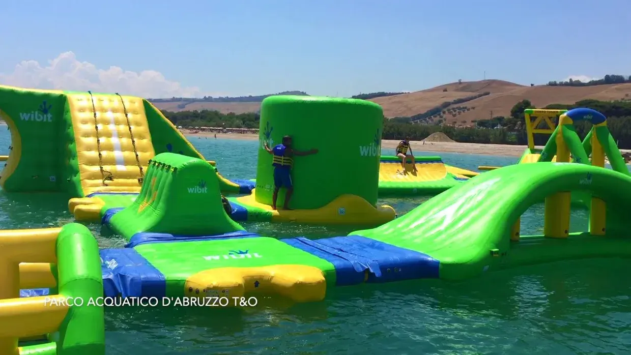 I gonfiabili colorati del parco acquatico sul mare, con le colline sullo sfondo