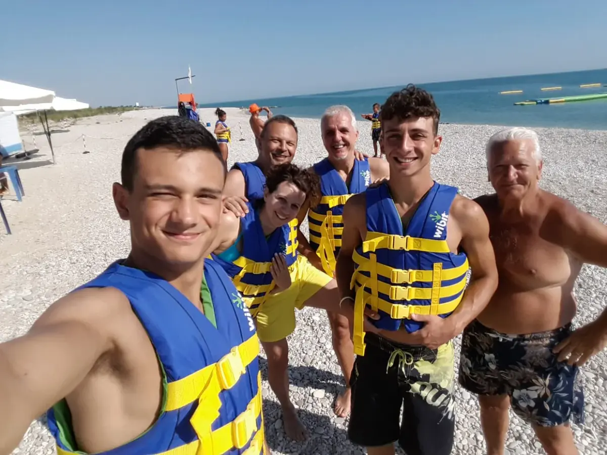 Un gruppo di ragazzi e adulti con il giubbotto salvagente sulla spiaggia