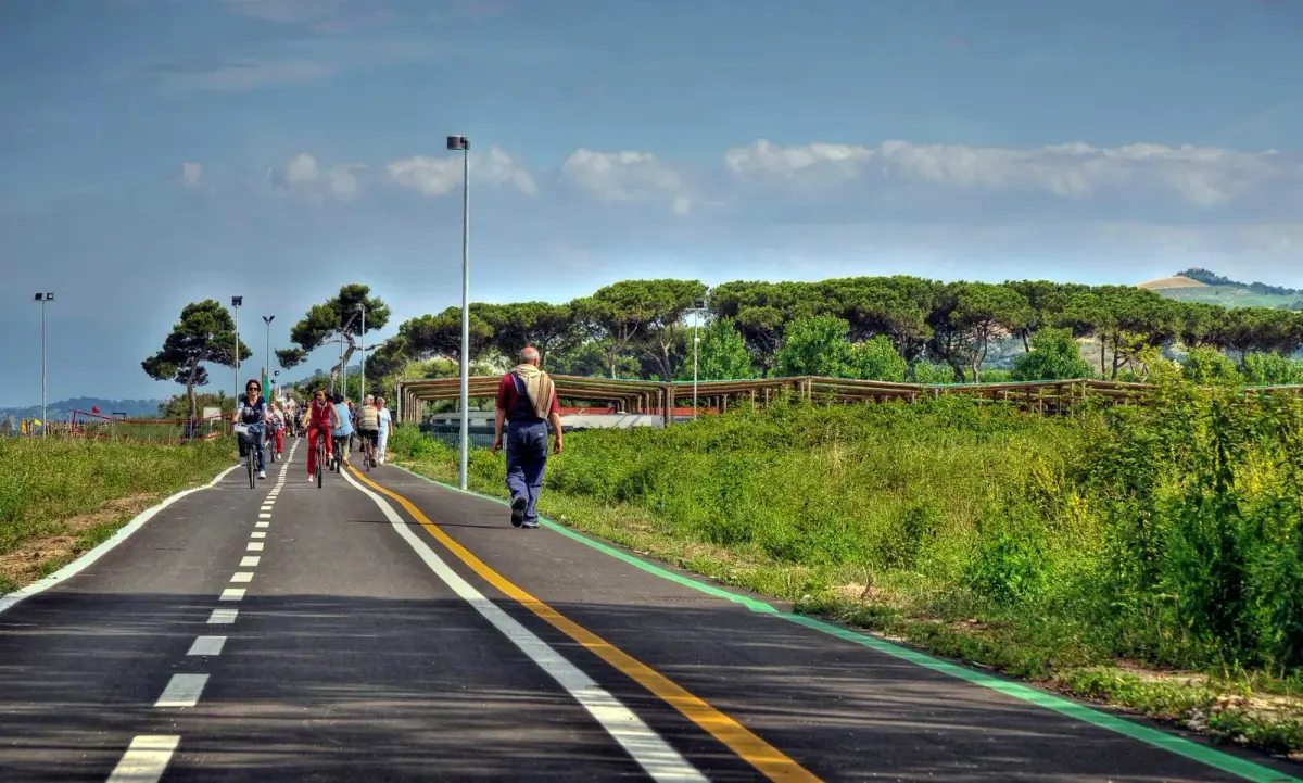 La pista ciclabile lungo il litorale, con persone a piedi e in bici e la pineta sullo sfondo