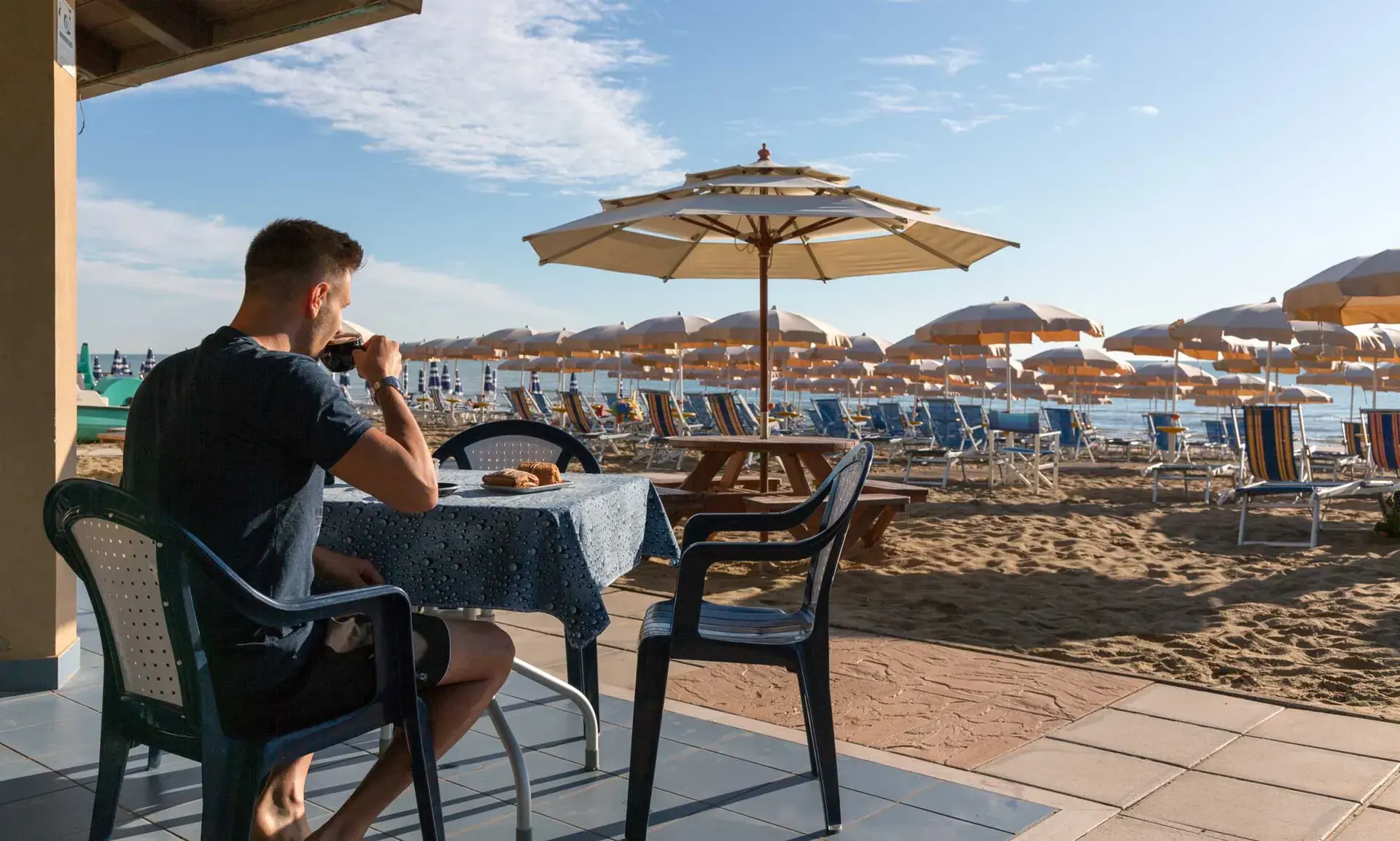 Un ospite al tavolo del beach bar affacciato sulla spiaggia del Lido Corfù