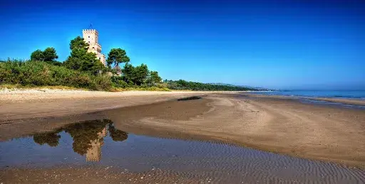 La Torre del Cerrano dietro la spiaggia, riflessa nell’acqua bassa